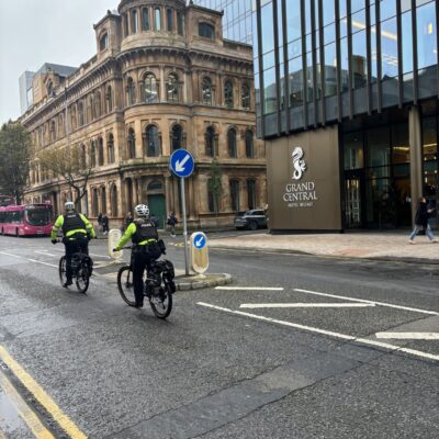 This image shows two police officers on bikes riding past the Grand Central Hotel on Bedford Street.