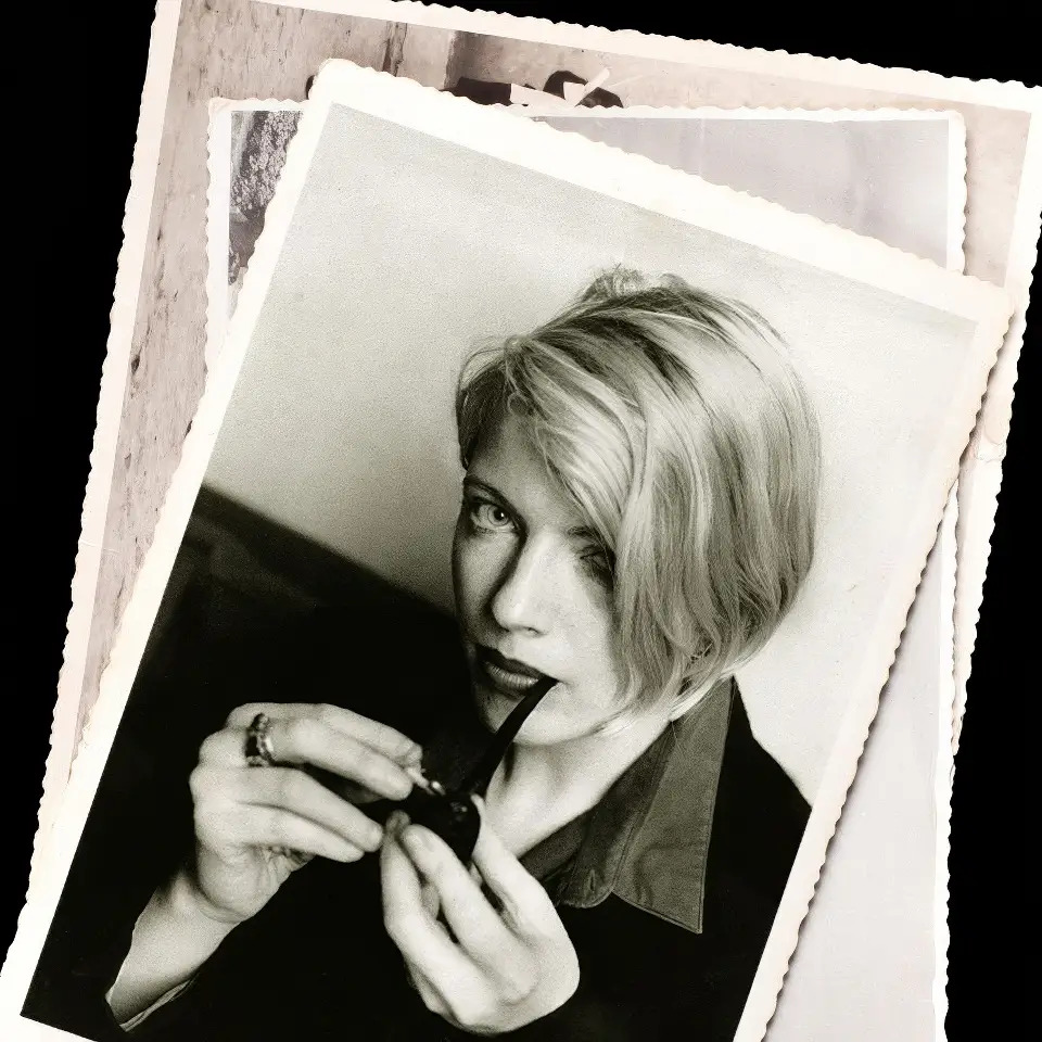 Image is a black and white poloroid style image of Brighid McLaughlin smoking a pipe