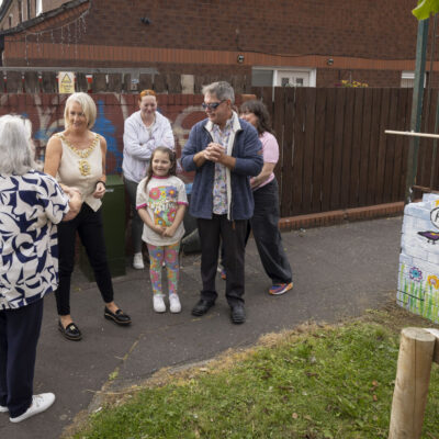 A group of people gather with the lord mayor alongside a mural